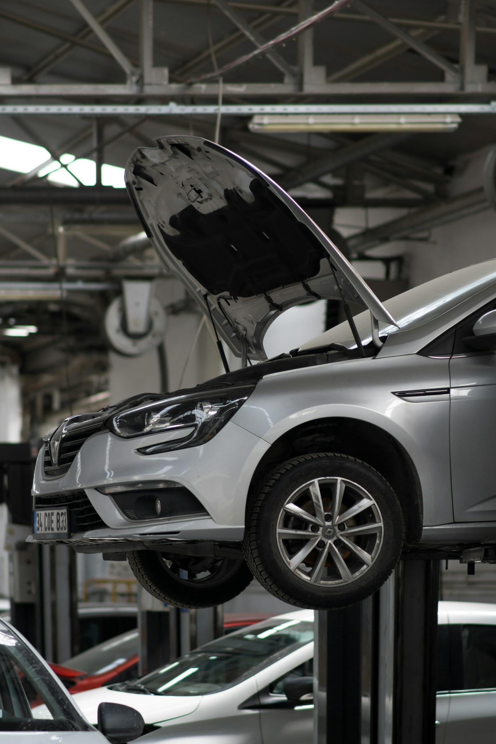 A car raised on a two-post ramp in the workshop with the bonnet up